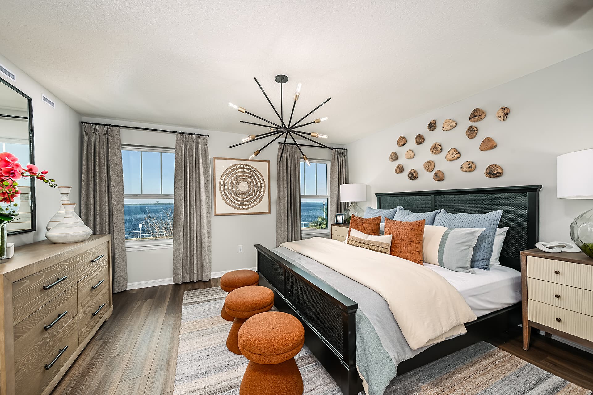 primary bedroom with black bed and orange stools