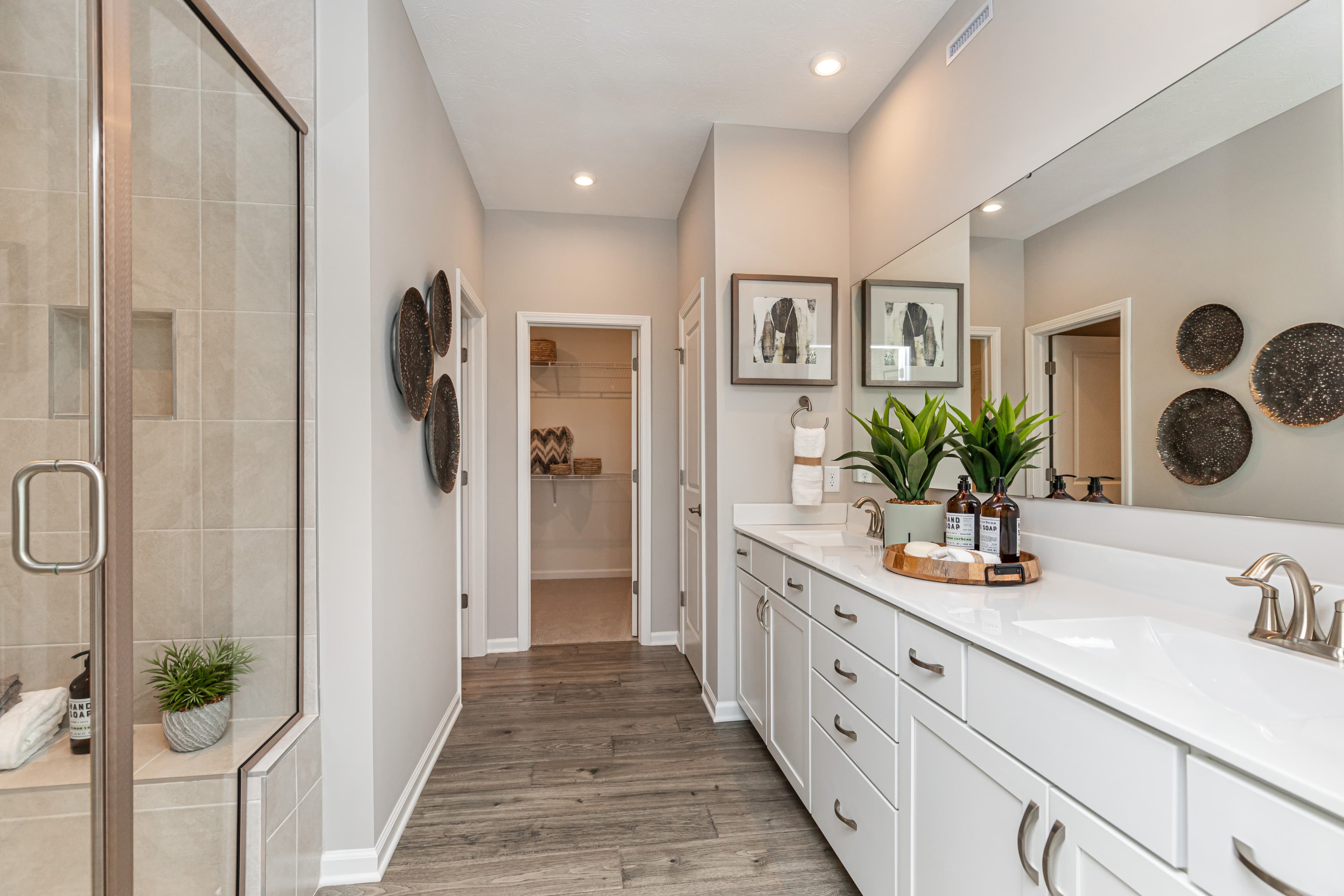 primary bathroom with tiled shower and two sinks 