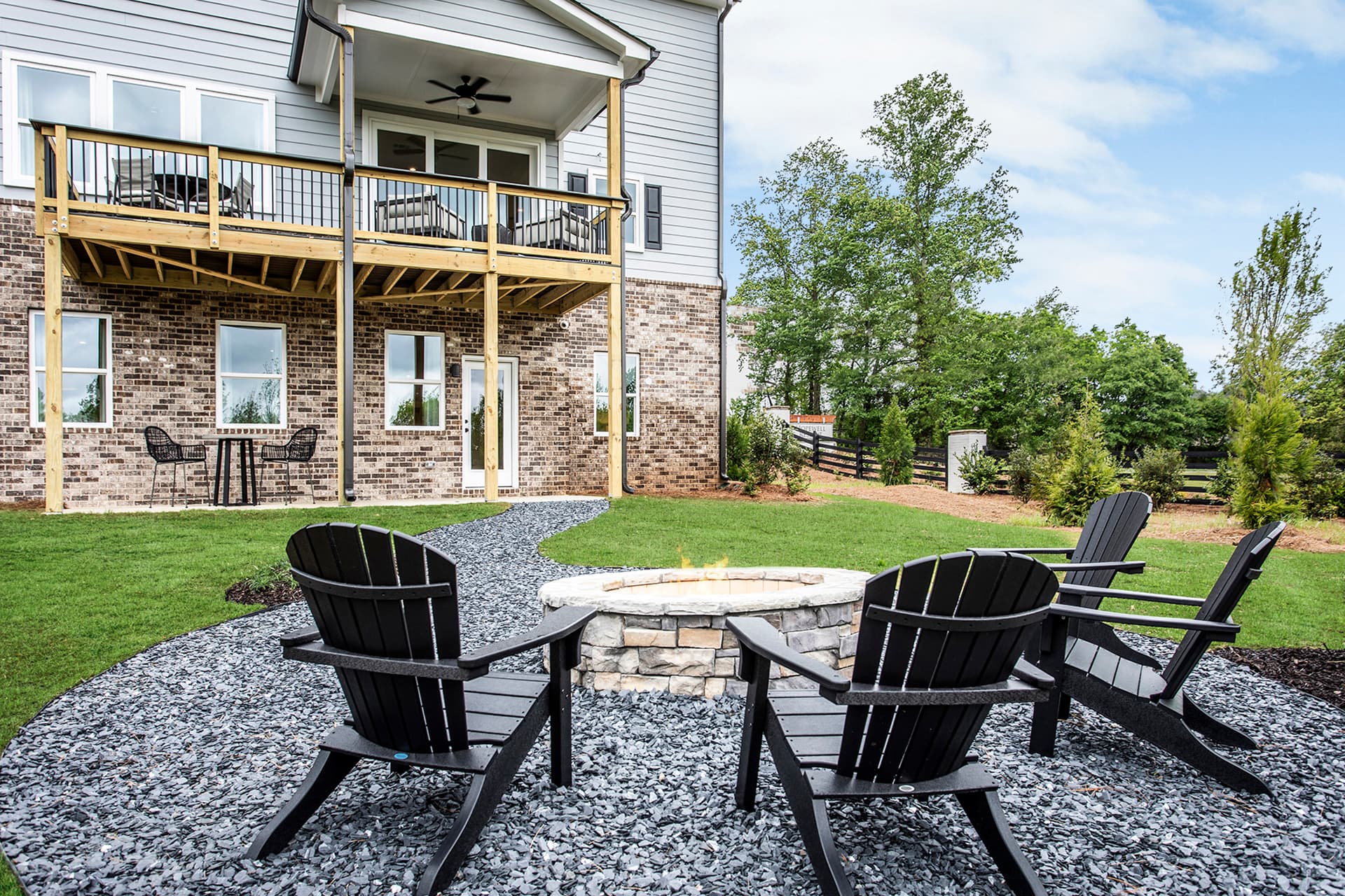 back of 2-story home with deck and firepit